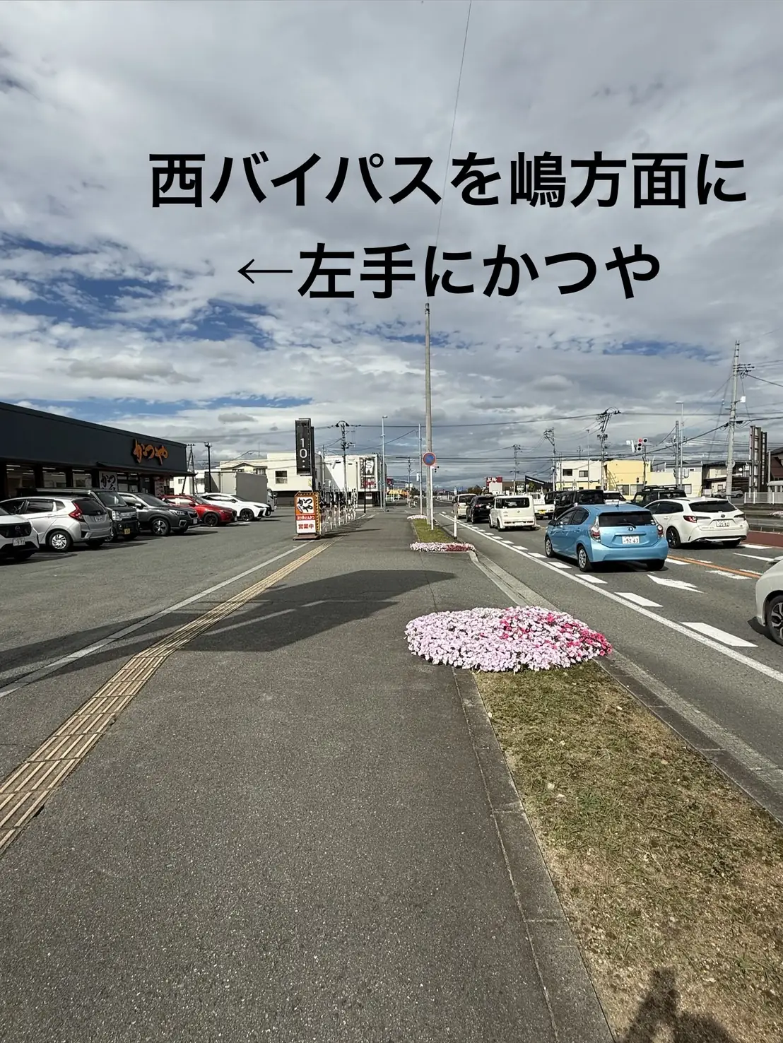 西バイパスを嶋・東根・天童方面へ進む道路。左手に「かつや」の店舗が見える。写真には「西バイパスを嶋方面に ←左手にかつや」と書かれている
